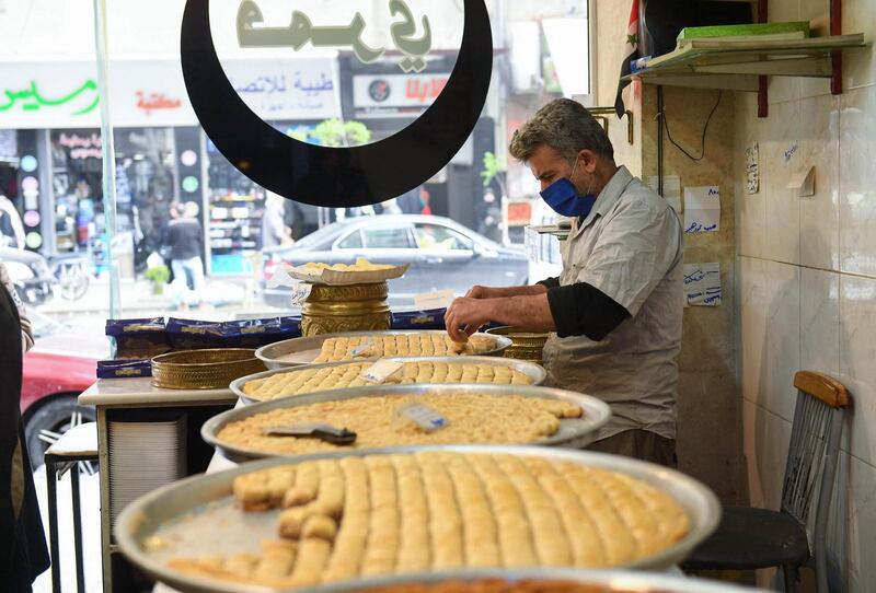 A pastry chef prepares Ramadan sweets for a customer as people shop ahead of the fasting month, in Syria's northern city of Aleppo. AFP