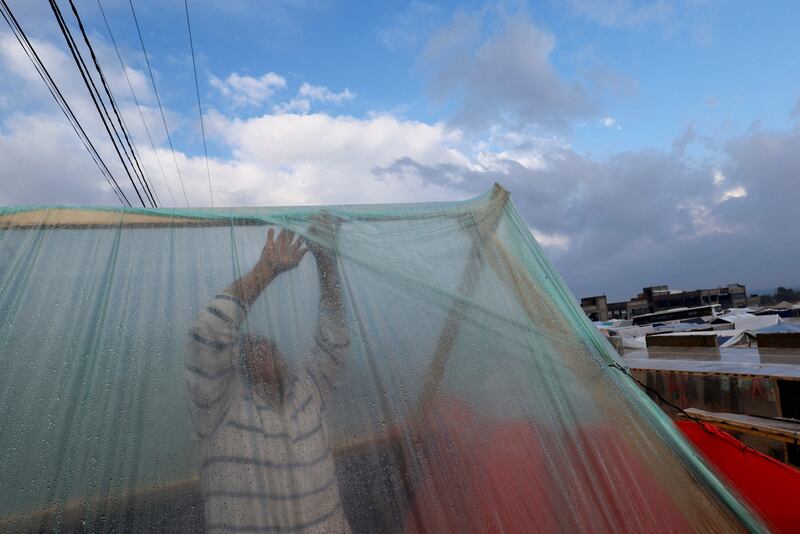 A displaced man adjusts his tent following heavy rains. Reuters