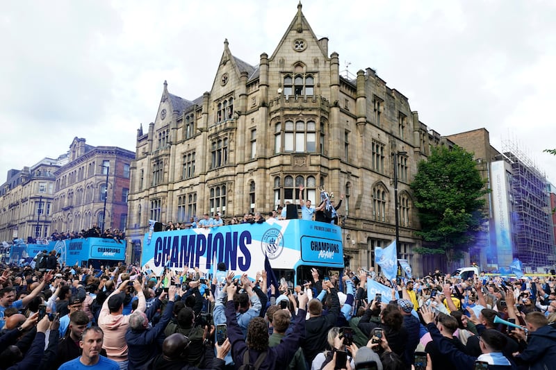 Fans celebrate as Manchester City players pass by. AP