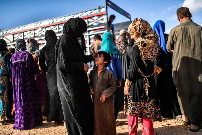 A displaced Syrian woman from the city of Deir Ezzor caresses her son as they wait to get bread on the outskirts of Raqa on October 2, 2017. 
Syrian fighters backed by US special forces are battling to clear the last remaining Islamic State group jihadists holed up in their crumbling stronghold of Raqa. / AFP PHOTO / BULENT KILIC