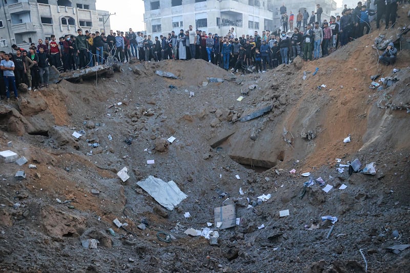 Palestinians stand on the edge of a crater after an Israeli strike in Rafah. AFP