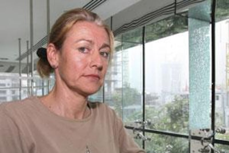 Christine Stewart stands next to a shattered glass pane in the Time Place Tower where she lives in the Dubai Marina.
