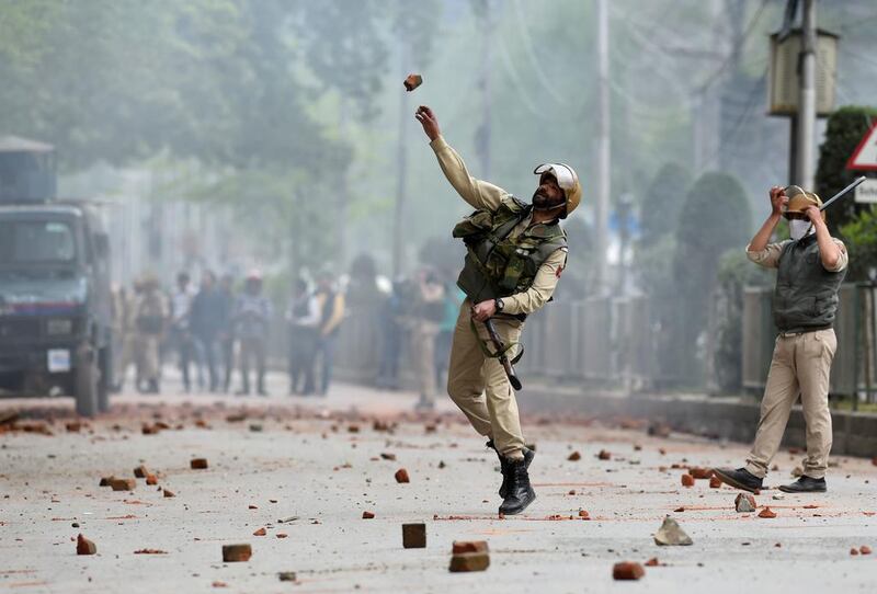 A member of the Indian security forces throws a stone during cashes with Kashmiri students in Srinagar's Lal Chowk area on April 24, 2017. Tauseef Mustafa / AFP

