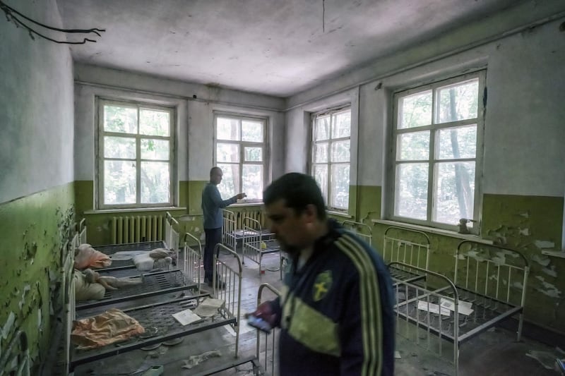 Tourists walk around rusty child-sized bed frames in a former preschool building. Bloomberg