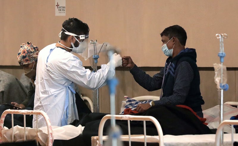 An Indian doctor wearing PPE bumps fists with a patient inside a Covid-19 care centre and isolation ward facility near a Hospital in New Delhi, India. The fist bump has become the norm during the pandemic. EPA