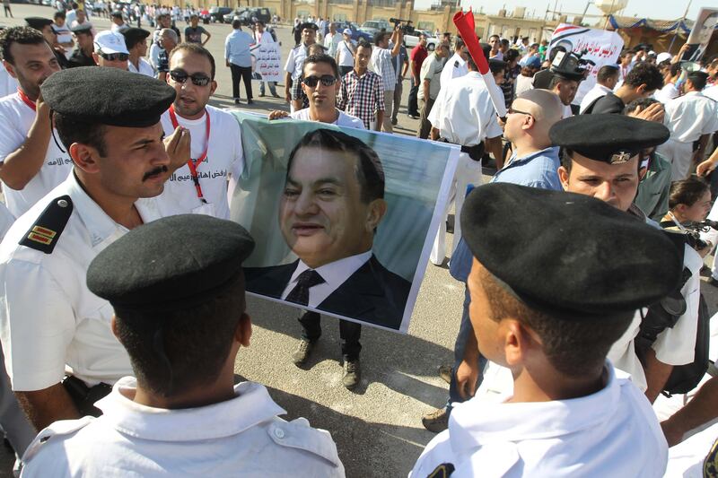Egyptian supporters of former president Hosni Mubarak hold up his poster as they stand in front of the police on the opening day of his trial at the police academy on the outskirts of Cairo, on August 3, 2011.  AFP PHOTO/KHALED DESOUKI
 *** Local Caption ***  543746-01-08.jpg