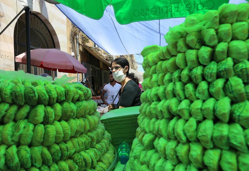 A woman wearing a face mask walks past sweets for sale for Eid, in Sidon, southern Lebanon. Reuters