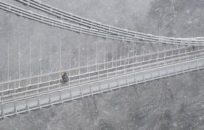 A person cycles over the Clifton Suspension Bridge and Avon Gorge in Bristol during snowfall in southwest Britain. REUTERS