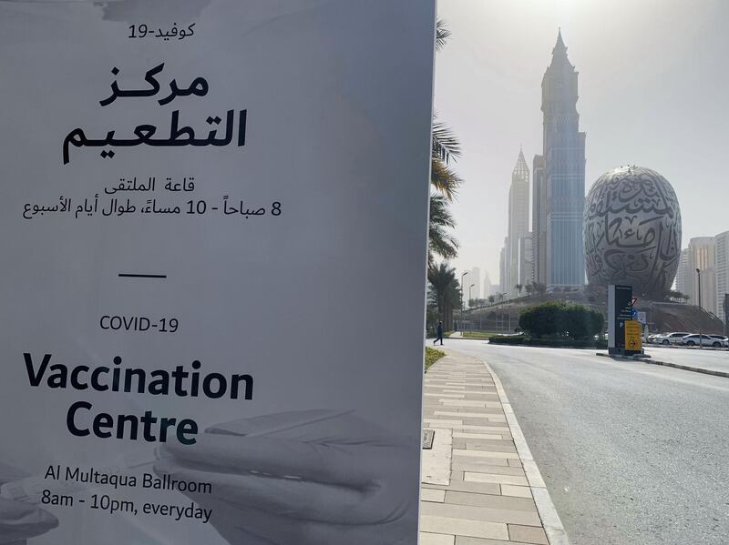 An advertisement placard informs the public of the location of a designated COVID-19 vaccination center at Dubai's financial center district, in the United Arab Emirates, on January 24, 2021. The emirate of Dubai has said it was slowing down its rollout of the Pfizer-BioNTech coronavirus vaccine due to a temporary delay in global deliveries. / AFP / Giuseppe CACACE
