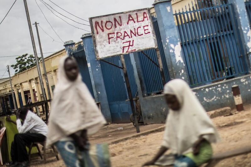 Two girls stand next to a sign with anti-France graffito and a Hindu swastika in the Muslim district of PK5 in Bangui. Marco Longari / AFP