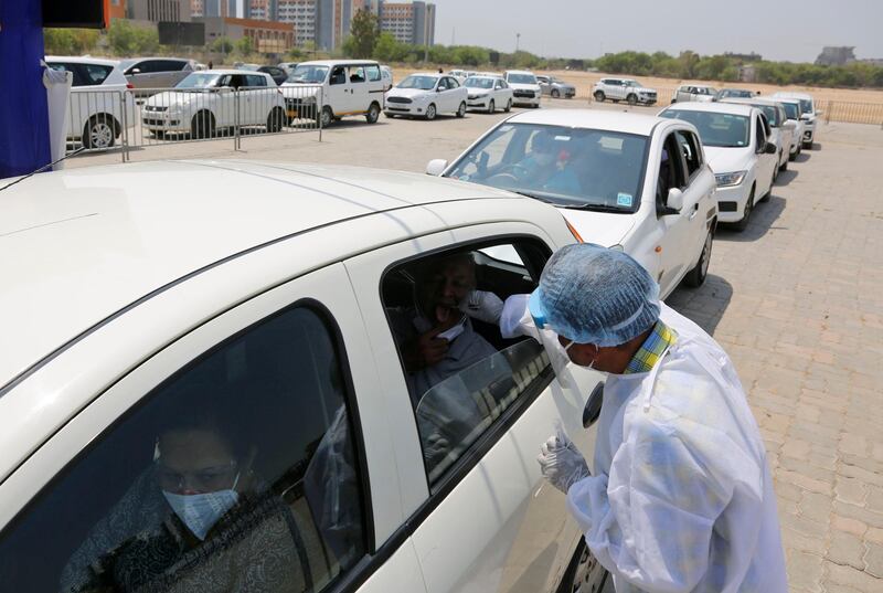 A health worker takes a swab sample to test for Covid-19 at a drive-through testing facility at GMDC ground in Ahmedabad, India. AP Photo