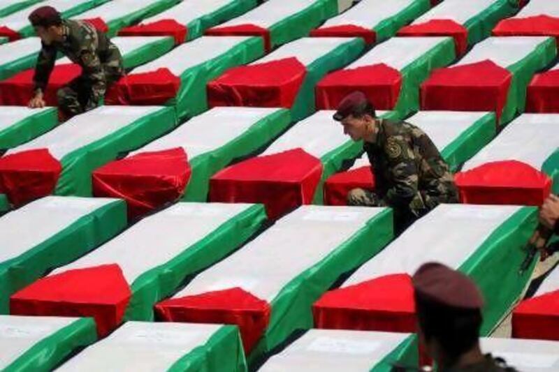 Palestinian security forces arrange Palestinian flags on coffins containing the remains of 91 fighters in the West Bank city of Ramallah. Israel handed over the remains to the Palestinian Authority yesterday as a goodwill gesture to encourage the resumption peace talks. Mohammed Ballas / AP Photo