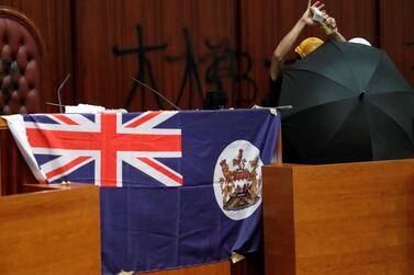 A protester tears a book of Hong Kong Basic Law as he stands next to a colonial flag of Hong Kong displayed inside a chamber after protesters broke into the Legislative Council building during the anniversary of Hong Kong's handover to China in Hong Kong. Reuters