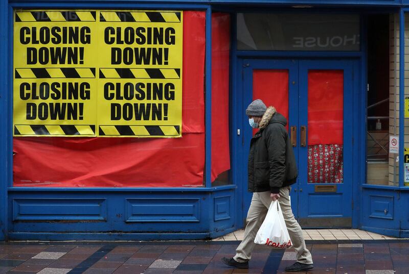 A man wearing a face mask to protect against coronavirus, walks past a closed shop in Stirling, Scotland.  AP