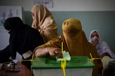 A burqa-clad woman casts her vote during Pakistan's general election at a polling station during the general election in Pehawar on July 25, 2018. Pakistanis vote on July 25 in elections that could propel former World Cup cricketer Imran Khan to power, as security fears intensified with a voting-day blast that killed at least 30 after a campaign marred by claims of military interference. / AFP / ABDUL MAJEED
