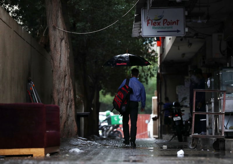 A man takes shelter under an umbrella during rain in Al Quoz, Dubai. Chris Whiteoak / The National