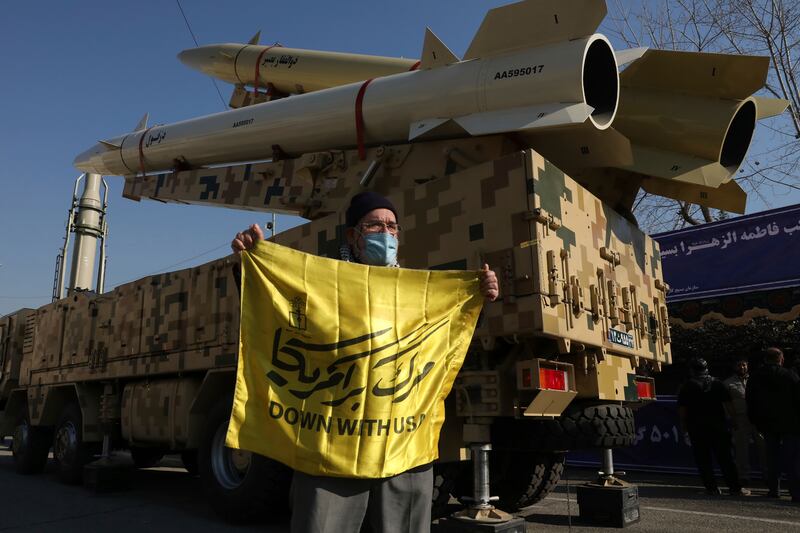 A man holds an anti-US banner in front of missiles displayed in an exhibition in Tehran, Iran. AP