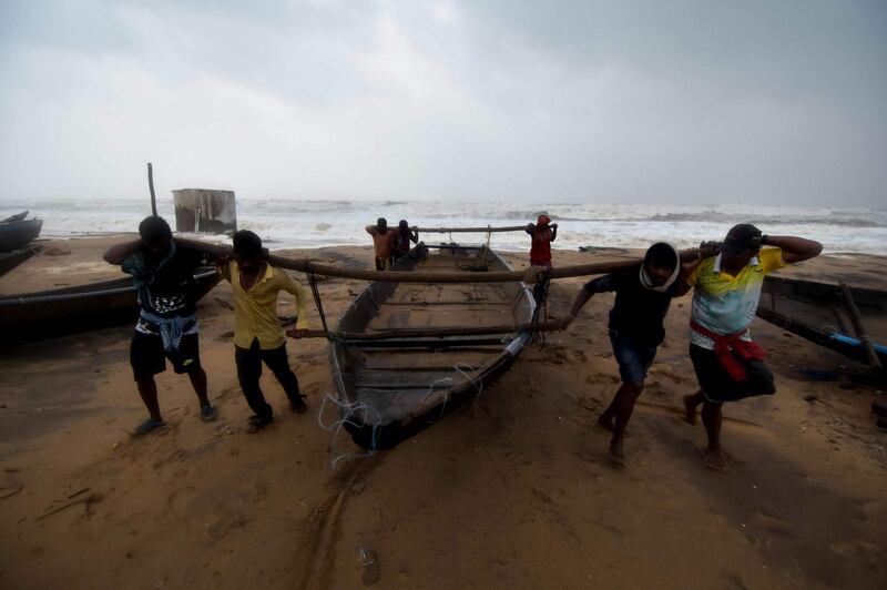 Men carry a fishing boat up a beach away from heavy waves brought by Cyclone Titli. AFP