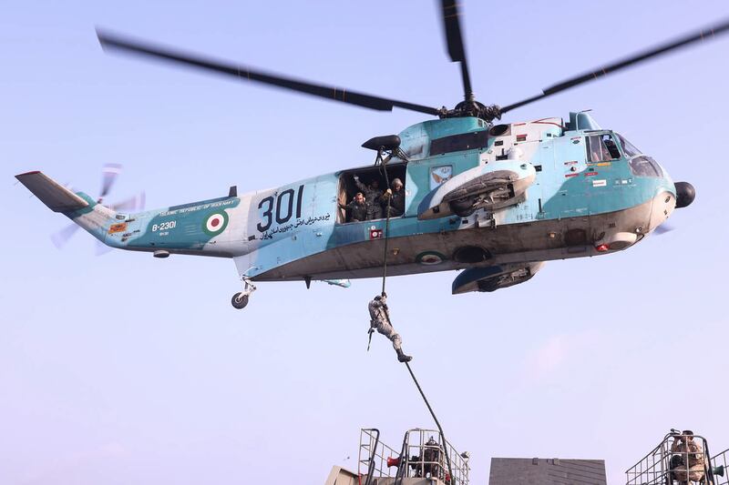 Soldiers rappel down a helicopter during the naval drill.