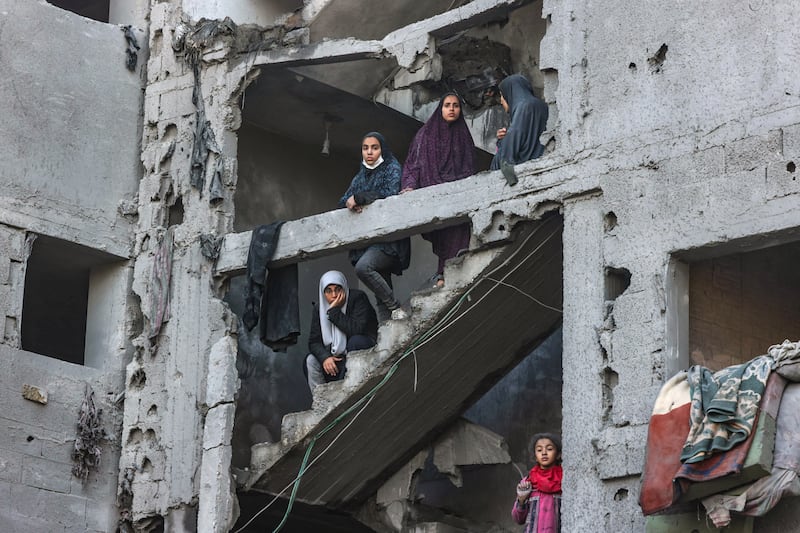 Palestinian women and children stand in the stairway of a badly damaged building. AFP