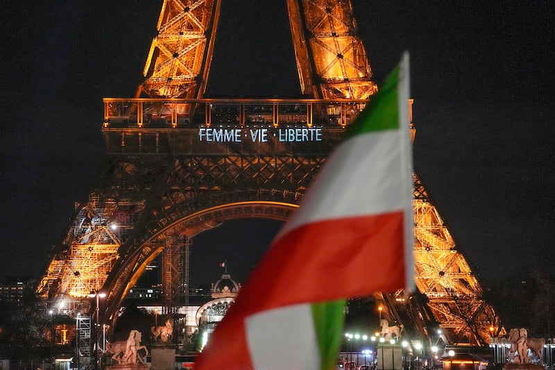 The Eiffel Tower lits the night with the a slogans "Woman, Life, Freedom" and "Stop Executions in Iran in support for the protests across Iran in Paris, Monday, January 16, 2023, as a Iranian flag flies next. AP