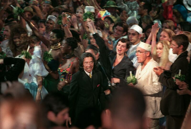 Fashion designer Kenzo Takada is surrounded by models as he acknowledges the audience following his final collection for next summer at the Zenith on October 7, 1999. AFP