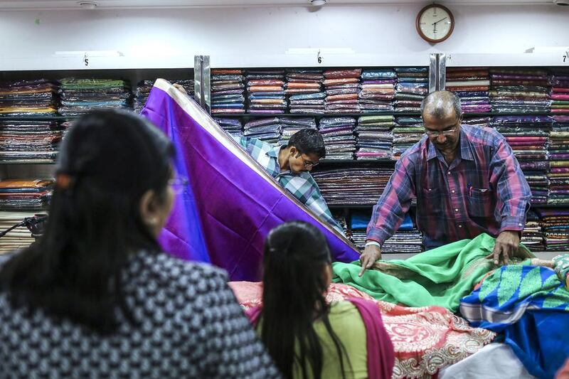 Salespeople display sarees to customers at the Roopmilan store in Mumbai. Dhiraj Singh / Bloomberg