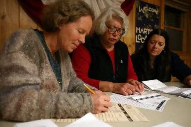 Election officials Nancy Ritger (L), Carolyn King (C) and Karen Faxon (R) tally up the votes in the US presidential election at a polling station just after midnight on November 4, 2008 in Hart's Location, the smallest town in the northeastern state of New Hampshire.  Residents of two tiny towns in New Hampshire, Hart's Location and Dixville Notch, symbolically kicked off voting in the US presidential election on Tuesday, November 4, 2008, casting ballots just after midnight. Hart's Location switched from its pro-Republican record to back a Democrat: Barack Obama won 17 votes there to 10 for his Republican rival John McCain, said an AFP journalist at the voting station, a simple trailer with a US flag hanging outside. Dixville Notch voted 15-6 in favor of Obama, who was leading in national polls, against McCain, CNN reported. It was the first time the location voted for a Democrat since 1968, the network said. With just 42 residents, Hart's Location claims the spotlight every four years, when it casts the first ballots for the presidency. The practice began in earnest in 1948, when town residents chose to vote at the stroke of midnight so that railroad employees could report to work on time in the morning.    AFP PHOTO / Jesse Baker *** Local Caption ***  629326-01-08.jpg