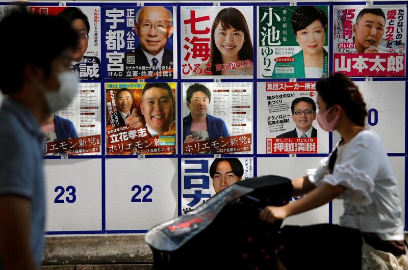 People wearing protective face masks walk past candidate posters for the upcoming Tokyo governor election during the spread of the coronavirus disease in Tokyo, Japan. Reuters