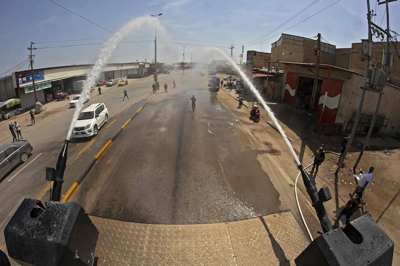 Iraqis use an anti-riot water-cannon vehicle to spray disinfecting liquid in the streets of the centre of the southern city of Basra.  AFP