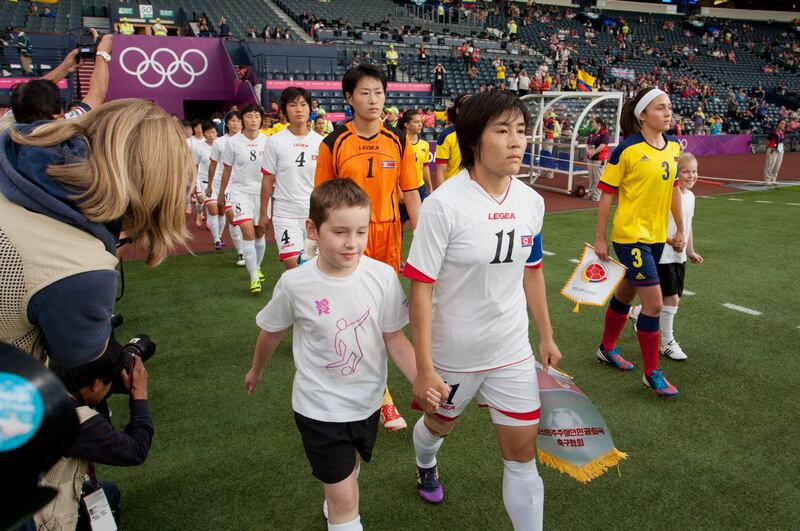 CORRECTS GROUP MATCH TO G INSTEAD OF B- The North Korean, center, and Colombian women's soccer team walk out on to the field before their group G match, prior to the start of the London 2012 Summer Olympics, Wednesday, July 25, 2012, at Hampden Park Stadium in Glasgow. (AP Photo/Chris Clark) *** Local Caption ***  CORRECTION London Olympics Soccer Women.JPEG-061e9.jpg