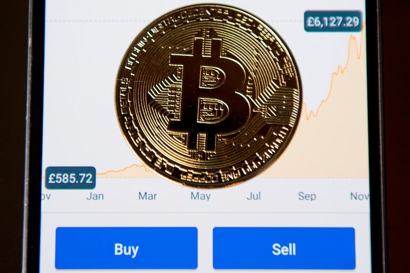 A gold plated souvenir Bitcoin coin is arranged for a photograph on a smart phone displaying current value of a single bitcoin, and options to buy or sell, on an app for the digital asset broker, Coinbase, in London on November 20, 2017.
Bitcoin, a type of cryptocurrency, uses peer-to-peer technology to operate with no central authority or banks. Bitcoin's recent rise and booming investor interest is forcing the regulatory and stock market authorities to formulate an official position on bitcoin and other virtual currencies, which are controversial not only because of their speculative nature, but are also seen as vehicles for illegal activities. / AFP PHOTO / Justin TALLIS
