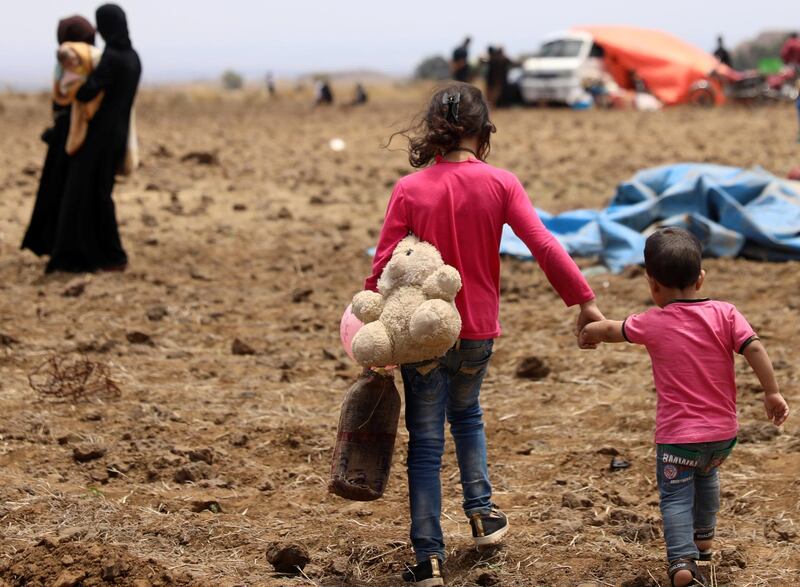 An Internally displaced girl from Deraa province carries a stuffed toy and holds the hand of child near the Israeli-occupied Golan Heights in Quneitra, Syria. Alaa Al-Faqir / Reuters