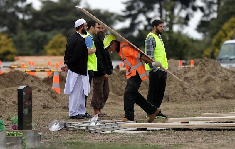 Muslims oversee the excavating of graves at a Muslim cemetery in Christchurch, New Zealand, Monday, March 18, 2019.  A steady stream of mourners paid tribute Sunday at a makeshift memorial to the 50 people slain by a gunman at two mosques in Christchurch, while dozens of Muslims stood by to bury the dead when authorities finally release the victims' bodies. (AP Photo/Mark Baker)