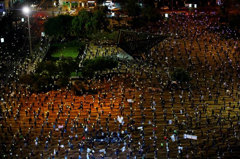 Israelis hold up their mobile phones as they demonstrate against Israel's Prime Minister Benjamin Netanyahu, under strict restrictions made to slow down the coronavirus spread, on Rabin Square in Tel Aviv, Israel April 19, 2020. REUTERS