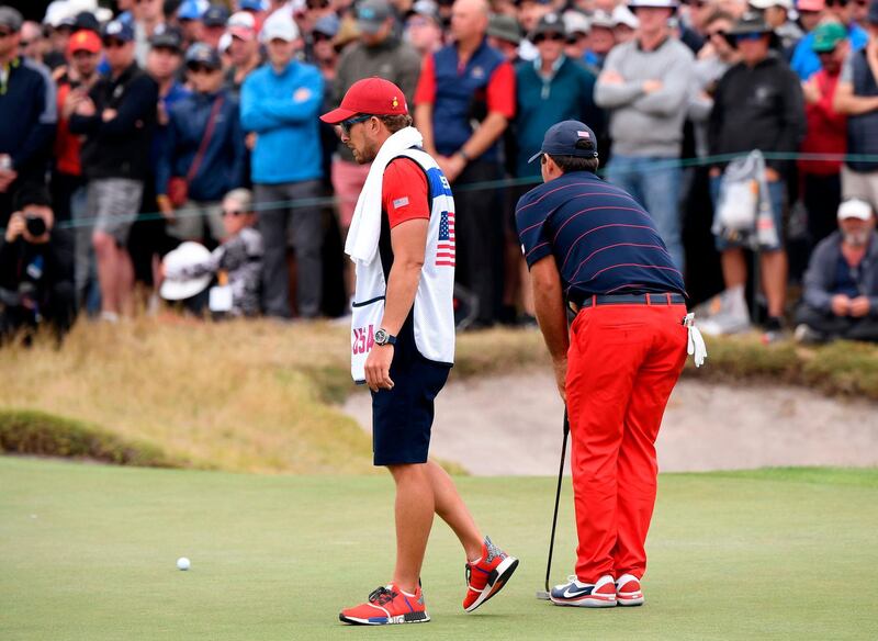 Kessler Karain (L) waits as his player Patrick Reed prepares to putt during the third day of the Presidents Cup. AFP