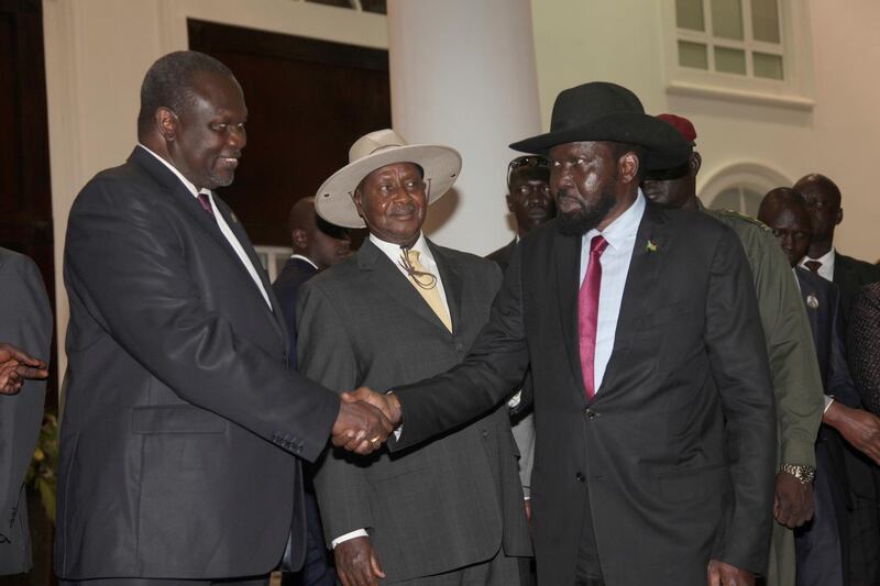 In this Saturday, July 7, 2018 photo, former Vice President of South Sudan Riek Machar, left, greets South Sudan President Salva Kiir as Uganda President Yoweri Museveni, center, looks on as they meet for a security meeting to find a lasting solution to insecurity in South Sudan, at the State House, in Entebbe, Uganda. (AP Photo/Stephen Wandera)