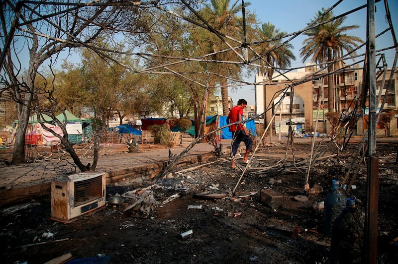 A protester inspects burned tents near Tahrir Square, Baghdad, Iraq. AP