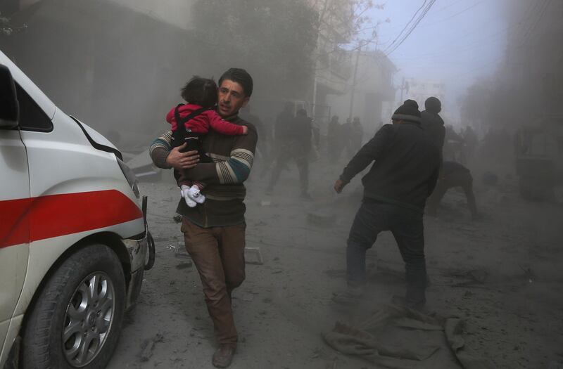 Civilians flee from regime air strikes in the rebel-held town of Saqba in the Eastern Ghouta region on February 8, 2018. Activists said the raids killed at least 75 people in the region on Thursday. Abdulmonam Eassa / AFP