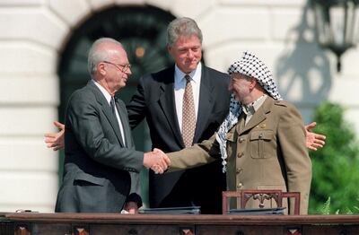 US President Bill Clinton (C) stands between PLO leader Yasser Arafat (R) and Israeli Prime Minister Yitzahk Rabin (L) as they shake hands for the first time, on September 13, 1993 at the White House in Washington DC, after signing the historic Israel-PLO Oslo Accords on Palestinian autonomy in the occupied territories. (Photo by J. DAVID AKE / AFP)