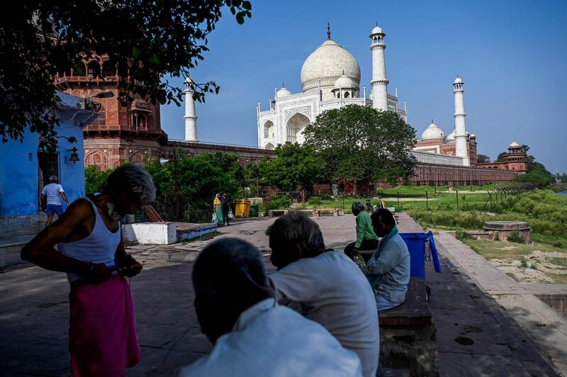 People rest under the shade of a tree near the Taj Mahal after it reopened to visitors. AFP