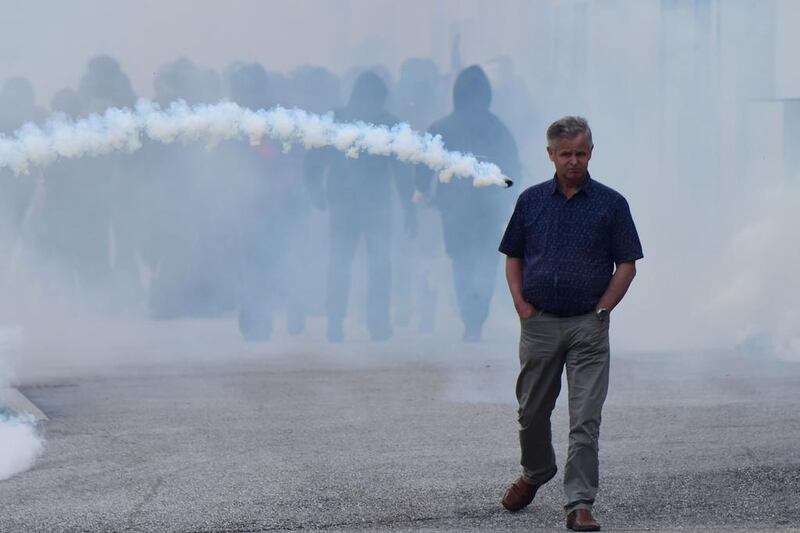 A man walks along a street as a smoke bomb is thrown during clashes between ‘No border’ activists andItalian police at the Brenner train station during demonstrations against Austria’s possible decision to close the border with Italy. Vienna is threatening to resume checks on the Brenner Pass between the two countries as part of a package of anti-migrant measures if Italy does not do more to reduce the number of new arrivals heading to Austria. Giuseppe Cacace / AFP