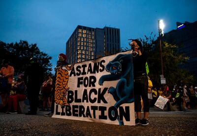 Demonstrators hold a banner reading 'Asians for Black Liberation' as they gather at the waterfront before walking to the Justice Center during a protest against racial injustice and police brutality on July 31, 2020 in Portland, Oregon. US federal officers will stay in the protest-wracked city of Portland until local law enforcement officials finish a "cleanup of anarchists and agitators," the US President said. The forces -- whose deployment was seen by many as part of the president's law-and-order strategy for re-election and exacerbated tensions between authorities and anti-racism protestors -- had been scheduled to begin their phased pullout from Portland on July 30. Law enforcement did not engage with the demonstration on Friday night. / AFP / Alisha JUCEVIC
