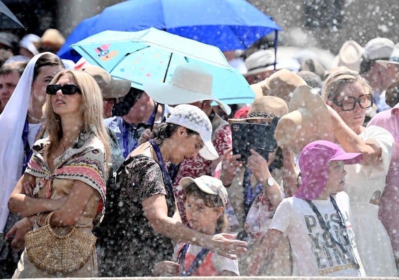 People cool off using water from a fountain on St Peter's Square in the Vatican City. AFP
