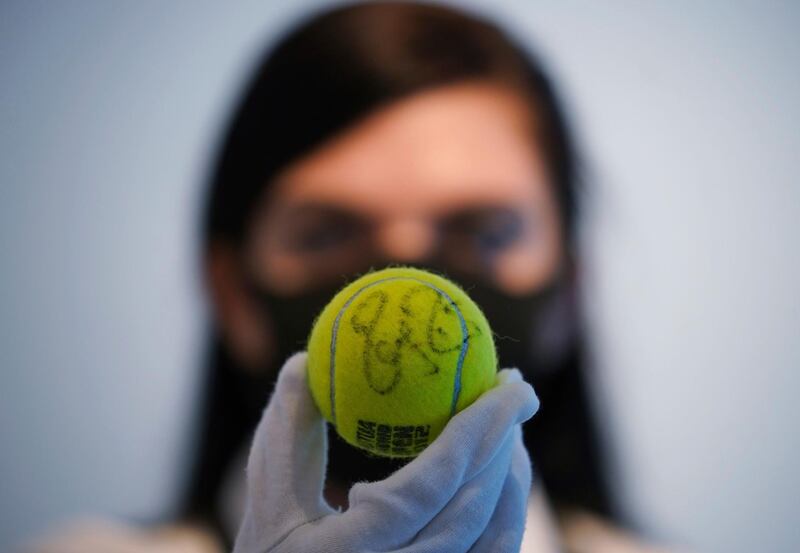 A Christie's technician holds up one of Swiss tennis player Roger Federer's signed Champion tennis balls from Madrid, 2012 at Christie's in London.