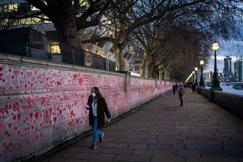 A woman passes Britain's National Covid Memorial Wall, in Westminster, London. The UK has recorded more than 200,000 coronavirus cases in a day for the first time. PA