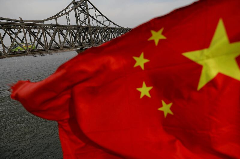 FILE PHOTO: A Chinese flag is seen in front of the Friendship bridge over the Yalu River connecting the North Korean town of Sinuiju and Dandong in China's Liaoning Province on April 1, 2017.  REUTERS/Damir Sagolj/File Photo