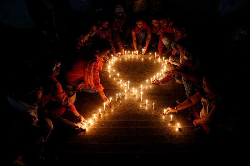 HIV campaigners make a red ribbon, the universal symbol of awareness and support for those living with the virus, with candles on the eve of World AIDS Day in Ahmedabad, India. Photo: AP