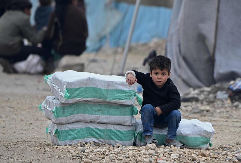 (FILES) In this file photo a displaced Syrian boy sits next to humanitarian aid, consisting of heating material and drinking water, at a camp in the town of Mehmediye, near the town of Deir al-Ballut along the border with Turkey, on February 21, 2020. Germany and Belgium have asked the UN Security Council to vote to extend authorization for cross-border humanitarian aid in Syria despite a likely Russian veto, diplomatic sources said on July 7, 2020. The German-Belgian draft resolution would extend for a year an authorization for aid to move into Syria, free from the control of the Damascus government, across two points on the Turkish border, while Russia wants one of the border crossings eliminated and only a six-month extension.
 / AFP / Rami al SAYED
