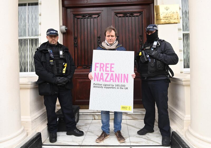 Richard Ratcliffe stands outside the Iranian Embassy as police look on. EPA